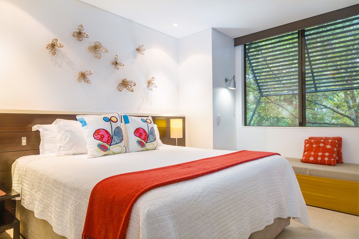 Bedroom with wire butterflies on the wall and an orange throw on the bed