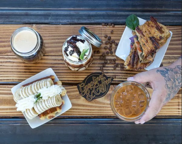 Overhead of iced coffee, waffles and a toasted sandwich on a timber table