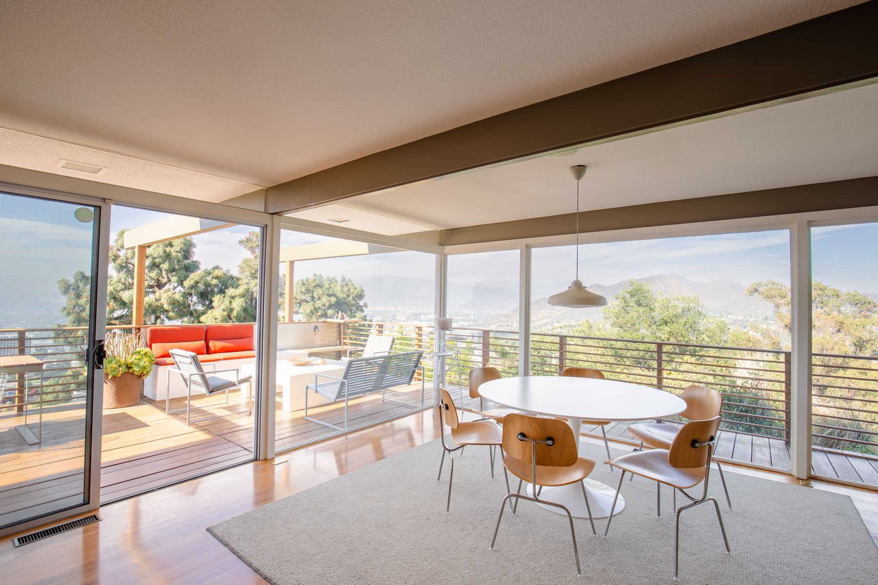 Dining table beside glass walls opening to a deck with mountain views