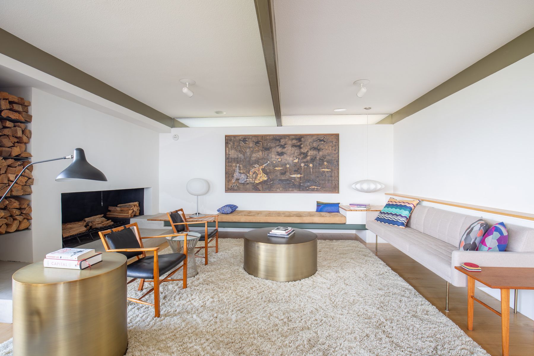 Mid-century living room with a log stack, brass tables and a long white sofa