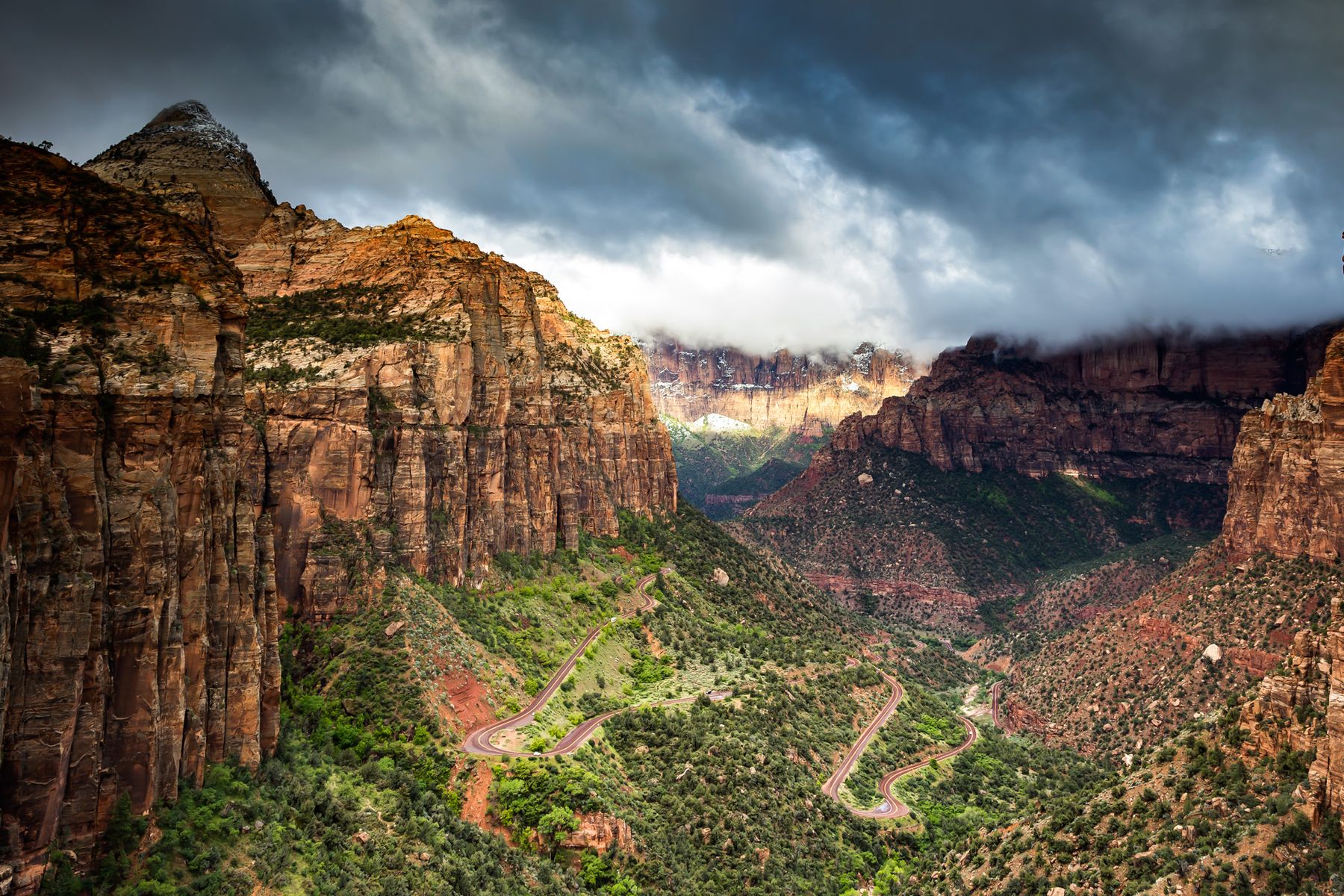 Storm clouds over red cliffs and switchback roads in Zion Canyon